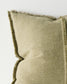 Textured green pillow with frayed edges on a light background