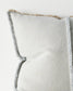 Textured pillow with frayed edges on a light background