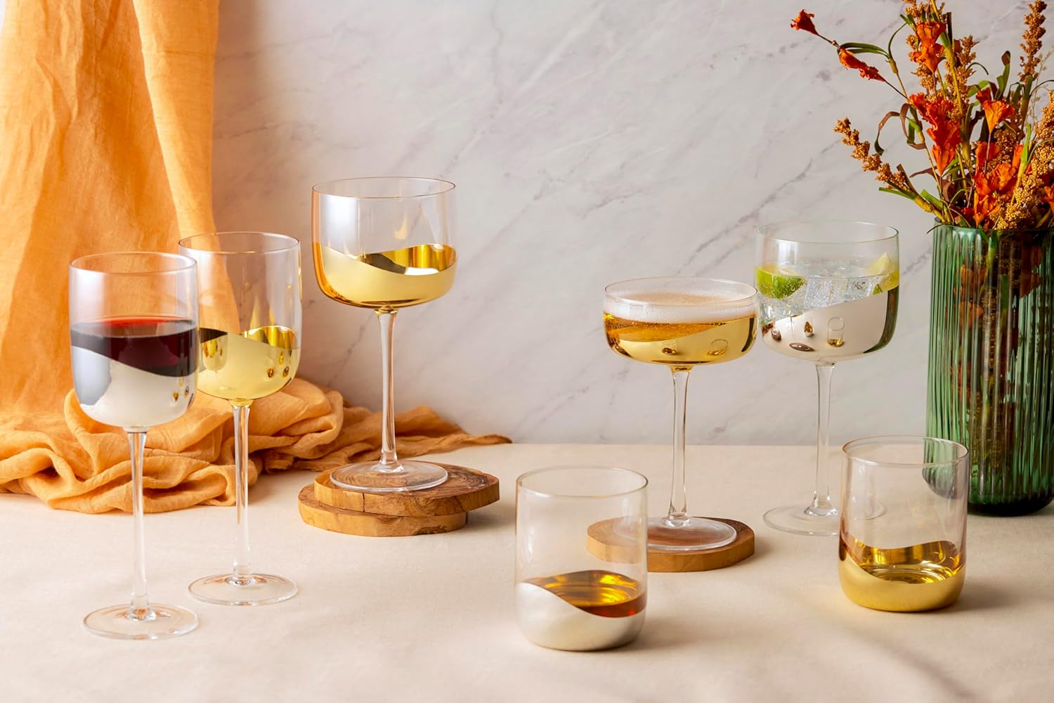 Set of wine glasses with different types of drinks on a table with a vase of flowers in the background.