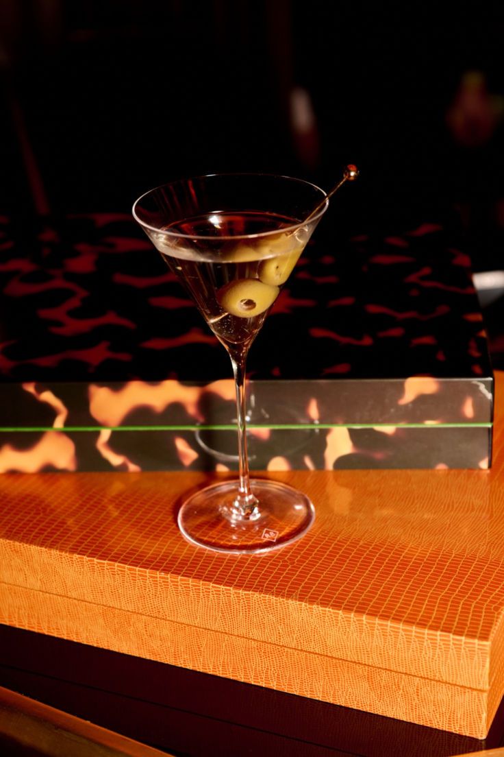 Martini glass with olives on a bar counter with a dark background