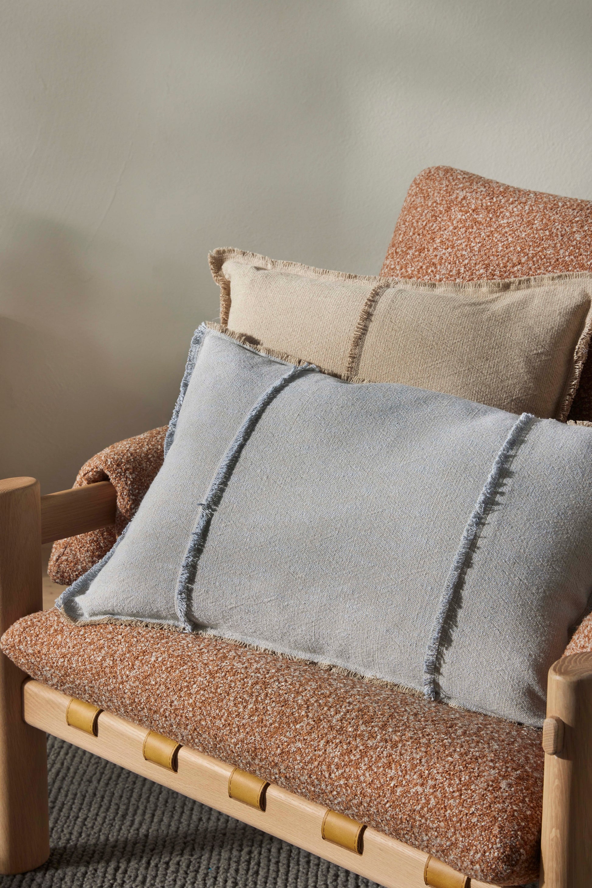 Gray pillow on a textured brown chair with a neutral background