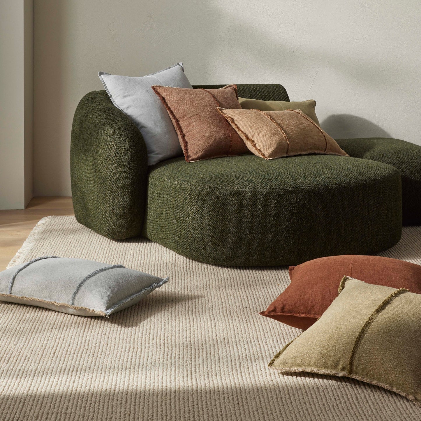 Green sofa with cushions in a minimalistic room