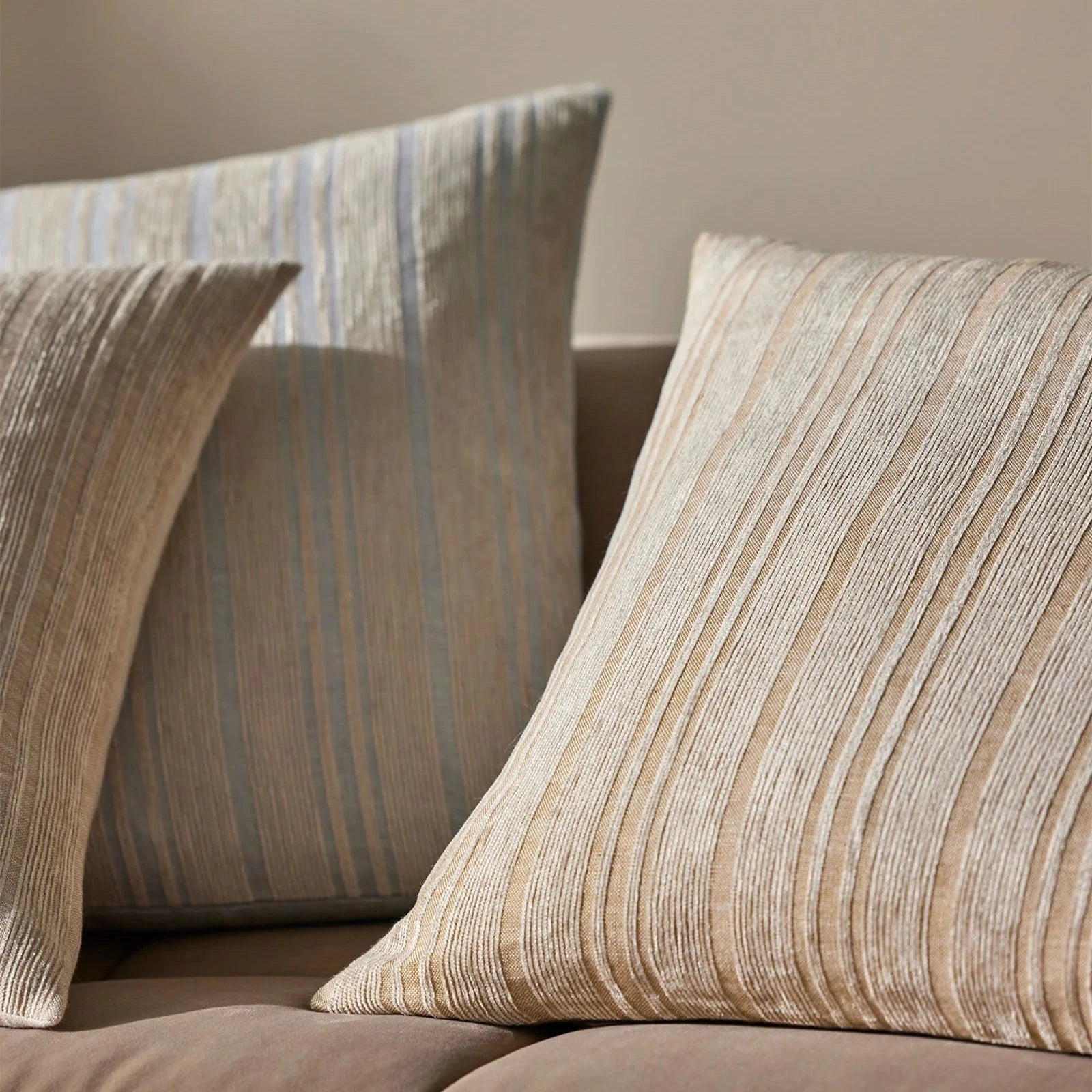 3 Adriana cushions in a lined chenille pattern on a beige sofa
