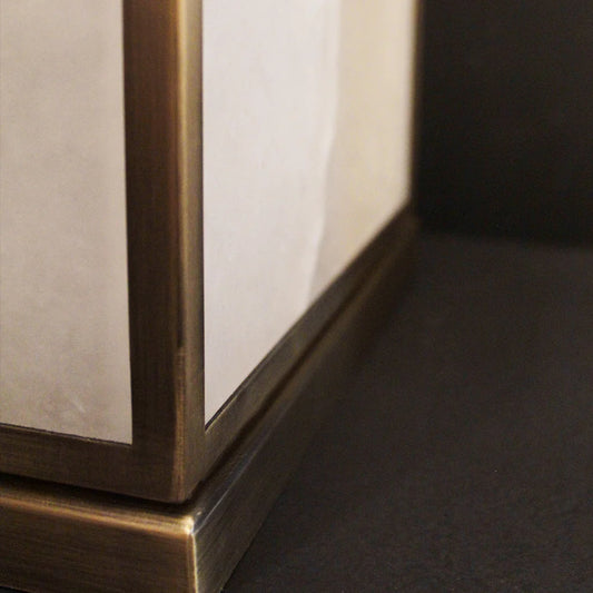 Close-up of a piece of table lamp with a brass frame and reflective surface.