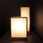 Two rectangular table lamps with white lampshades on a dark background