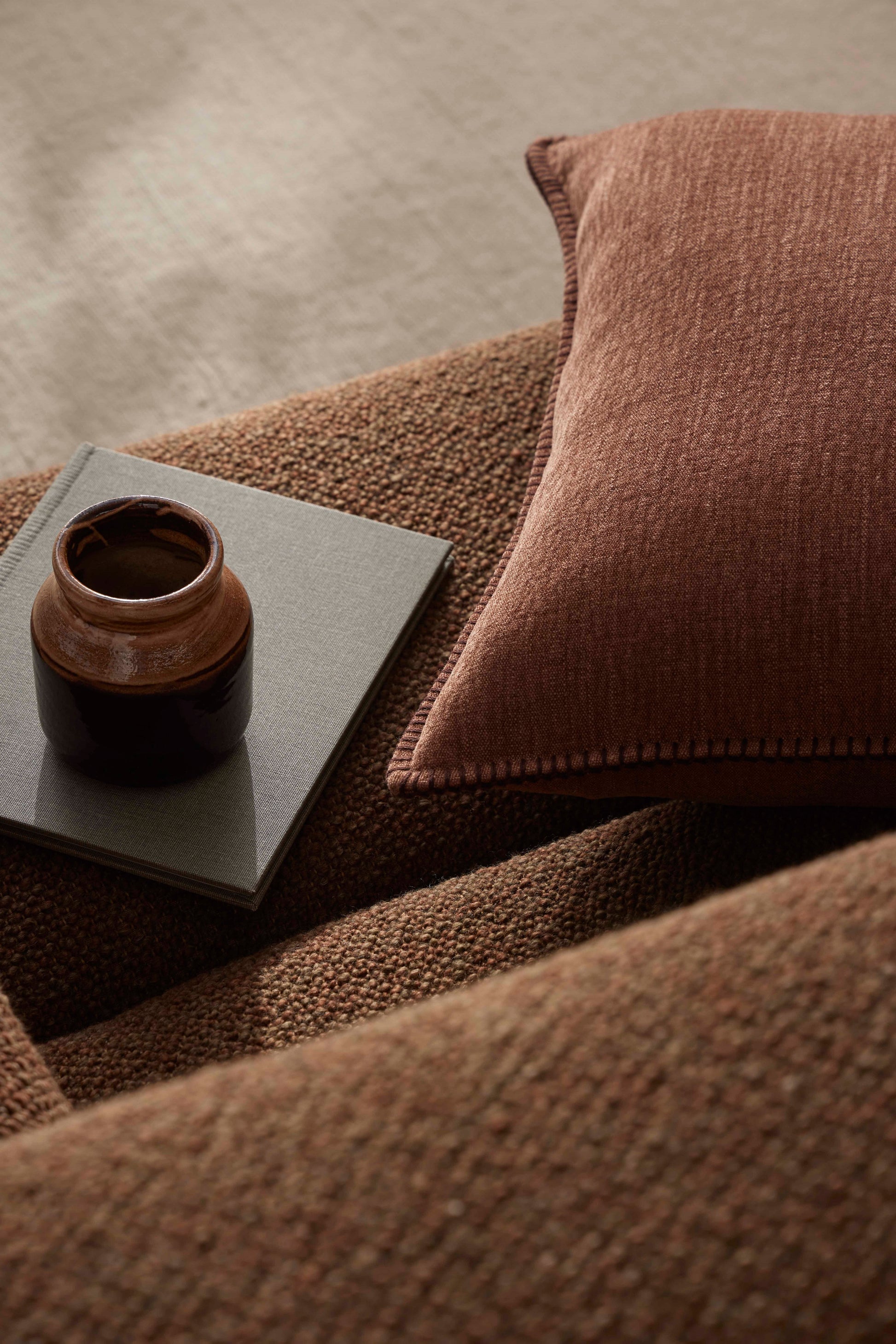 Ceramic vase on a textured surface with a pillow in the background