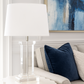 Living room with beige sofa, blue pillows, and a glass lamp.
