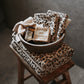 Leopard print towels and soap in a bowl on a wooden stool with a neutral background