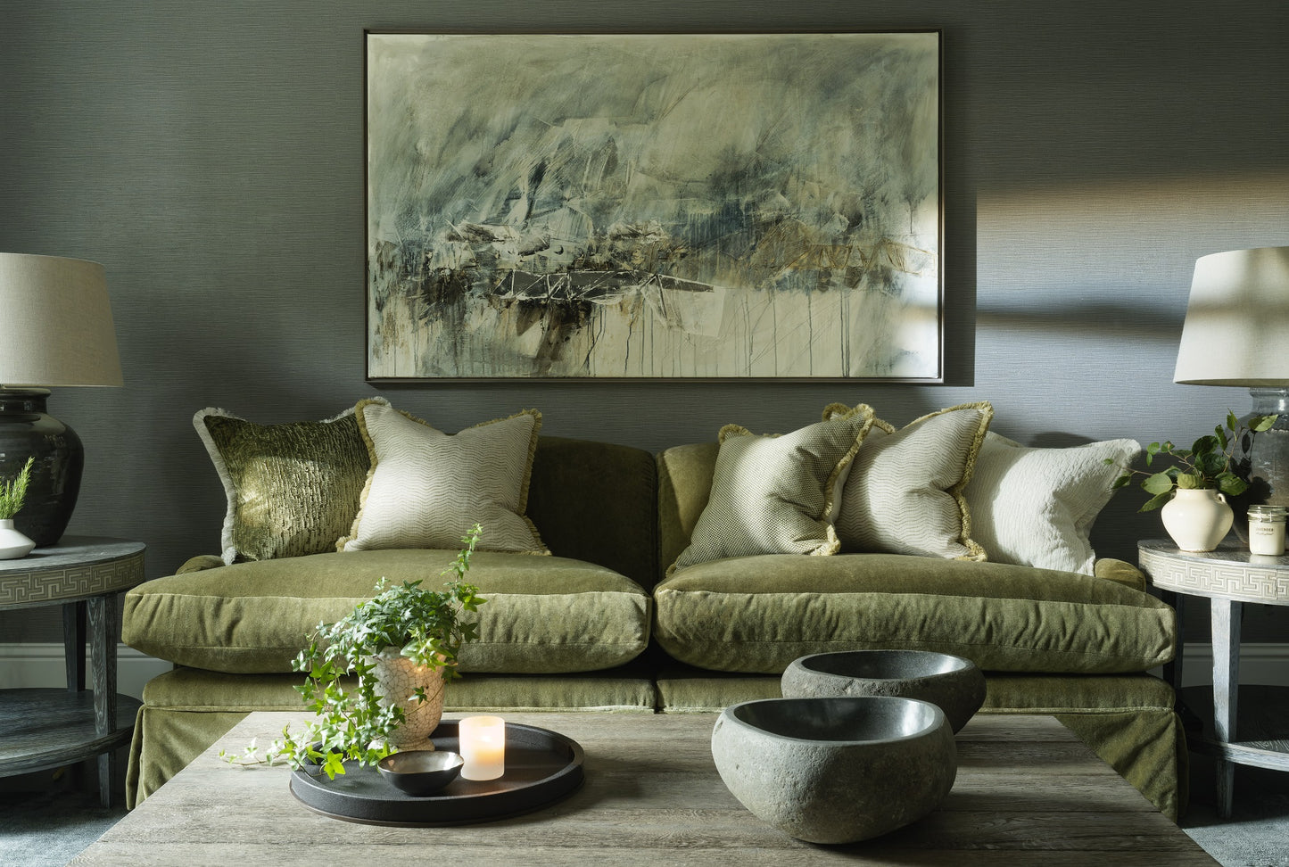 Living room with a green sofa, abstract painting, and decorative items.