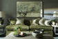 Living room with a green sofa, abstract painting, and decorative items.