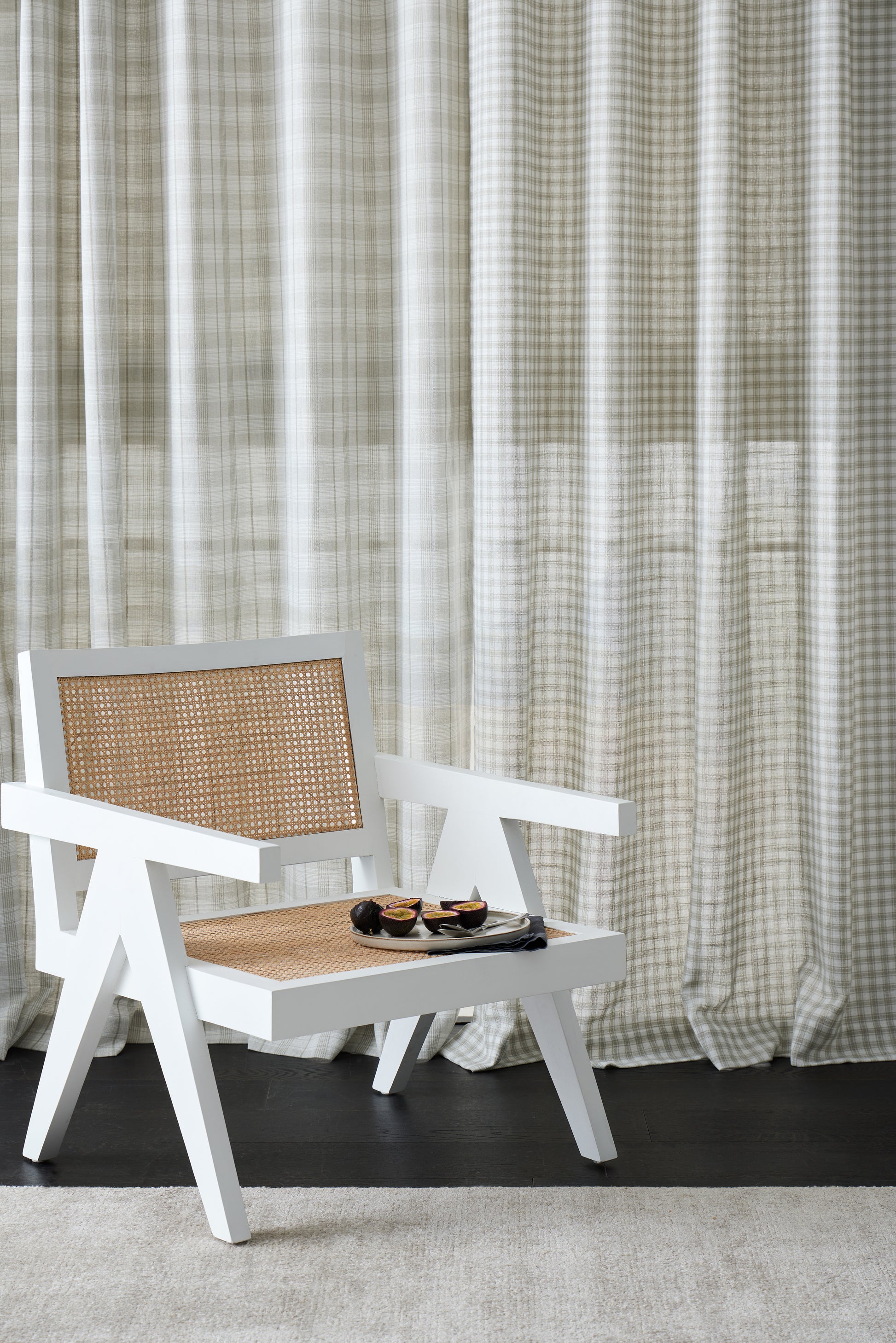 White chair with woven backrest in front of a curtain