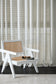 White chair with woven backrest in front of a curtain