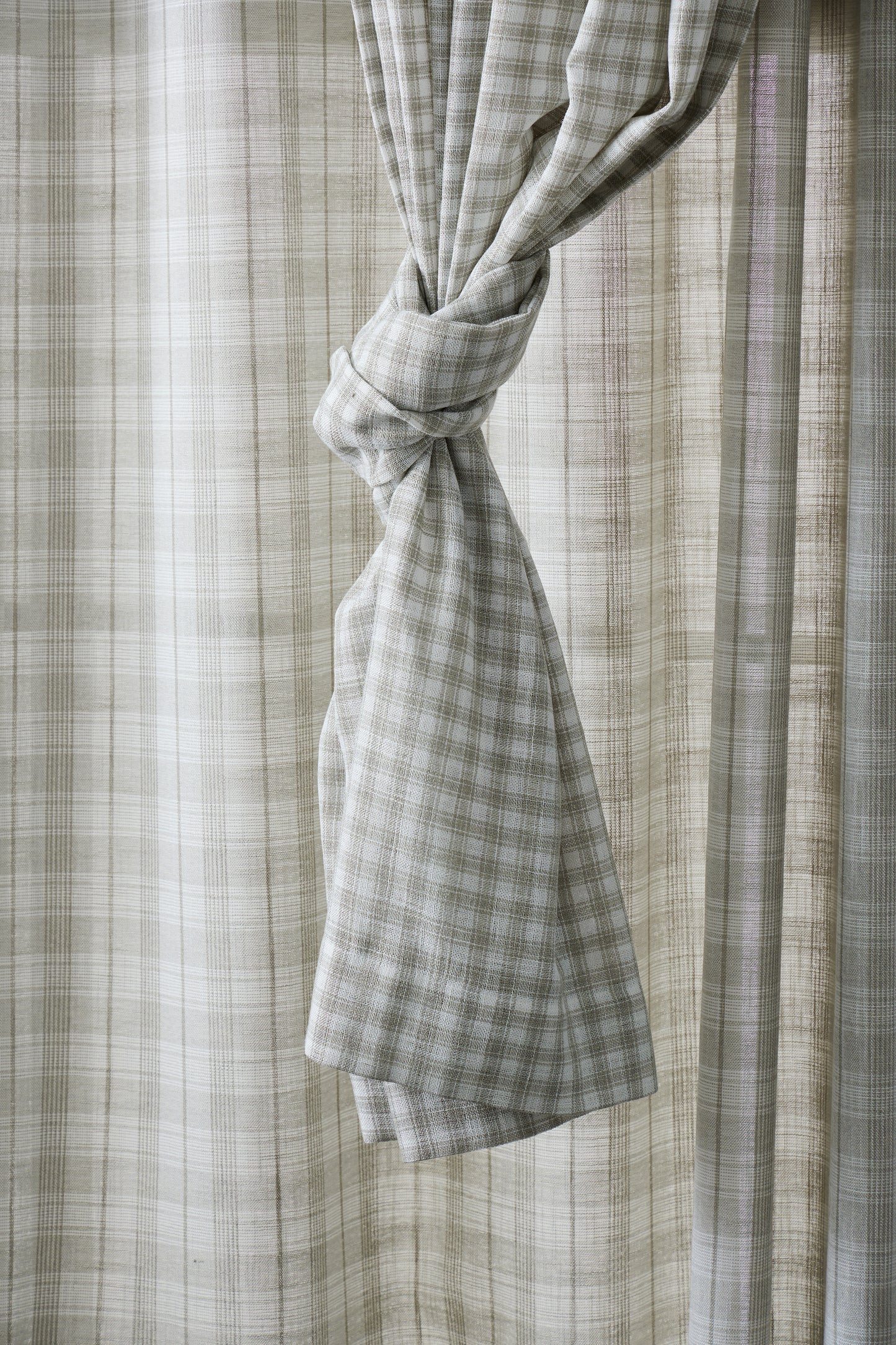 Plaid curtain tied back with a neutral background