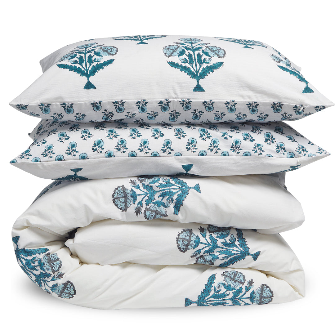 Stack of white bedding with blue floral patterns on a white background
