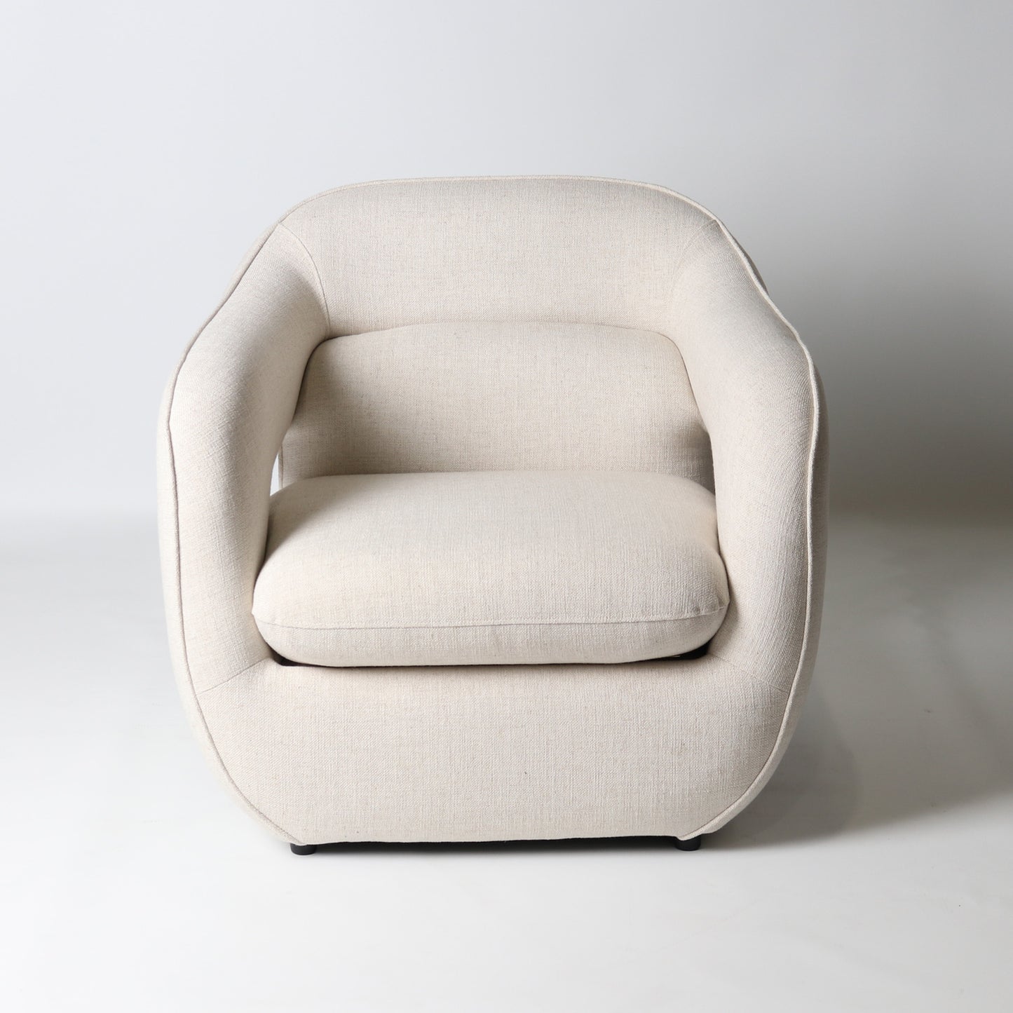 Architectural rounded open sided lounge chair in neutral fabric - front view