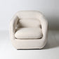 Architectural rounded open sided lounge chair in neutral fabric - front view