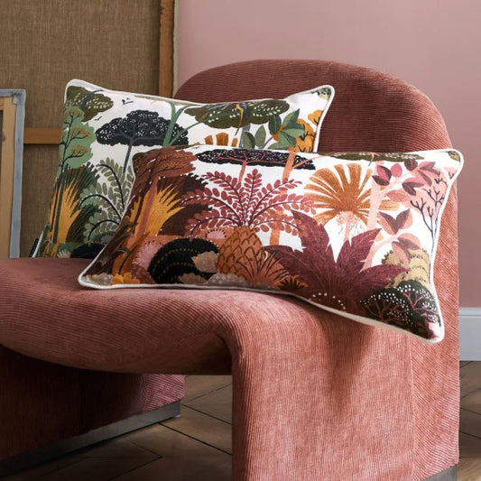 2 Ava cushions siting on a modern terracotta courdroy chair without arms. the cushions are a mix of terracottas, browns, gold and burgundy foliage on one and sage, olive, navy and gold on the other
