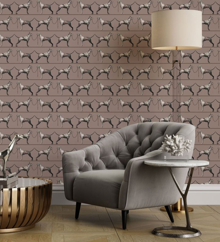 Living room with a gray sofa, side table, and decorative items against a wall with dog patterned wallpaper.