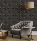 Gray tufted sofa in a room with dark gray walls featuring a dog pattern, a small round table, and decorative items.