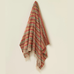 Woven blanket with red and green pattern on a beige background