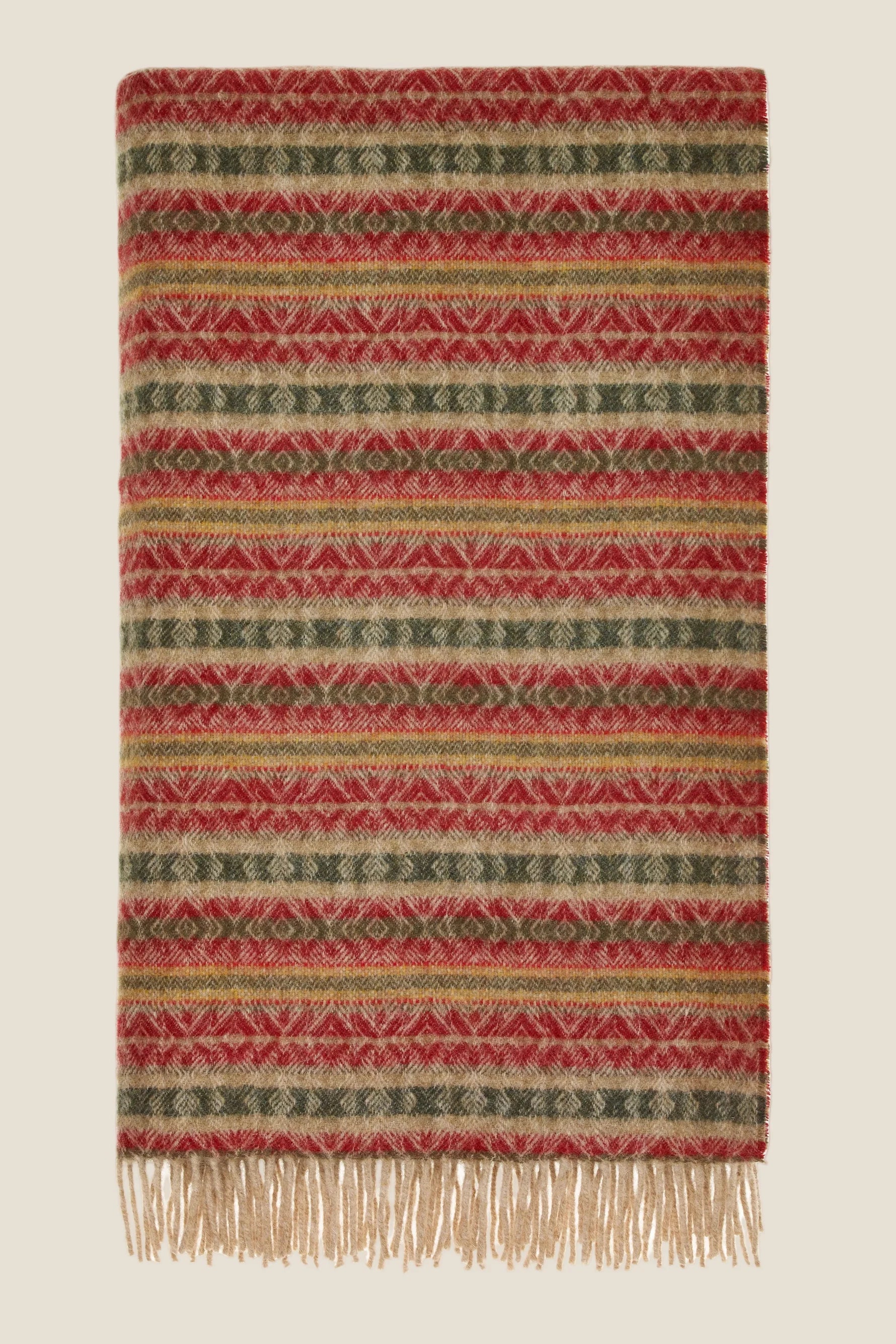 Woven blanket with red and green pattern on a beige background