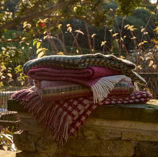 Stack of colorful checkered blankets on a stone ledge with a garden background