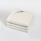 A folded off-white quilted comforter or duvet with a visible BAKSANA label, photographed on a clean light gray studio background.