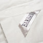 Close-up of a white fabric garment with a satin label reading BAKSANA in dark lettering.