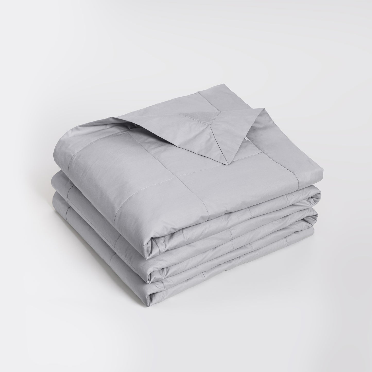 A folded light gray quilted comforter or duvet with a matching pillowcase, neatly stacked on a clean white studio background. Feather filled