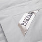 Close-up of a light gray quilted fabric with a diagonal satin label printed with the brand name 'BAKSANA' in dark lettering.