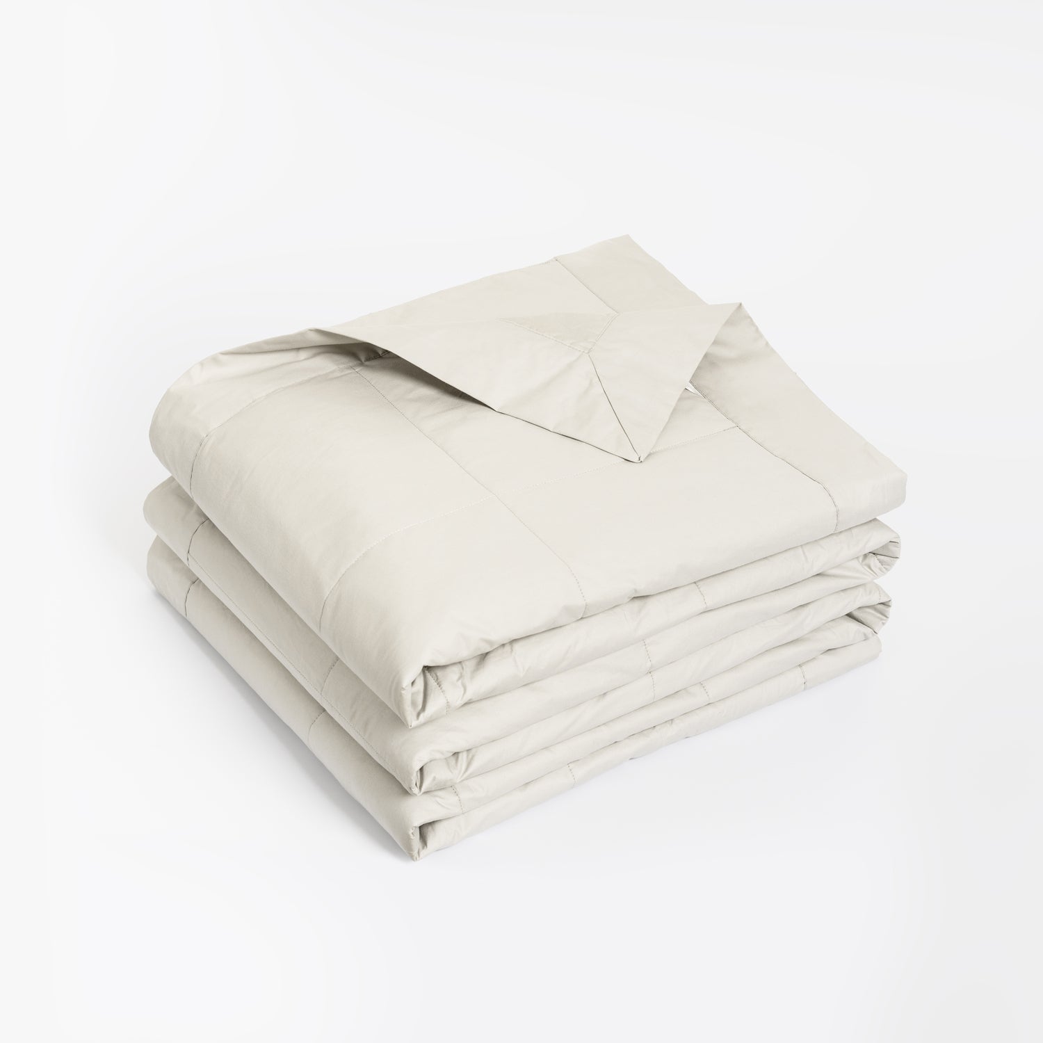 A folded light beige quilt or comforter with stitched channel tufting, shown on a clean white background.