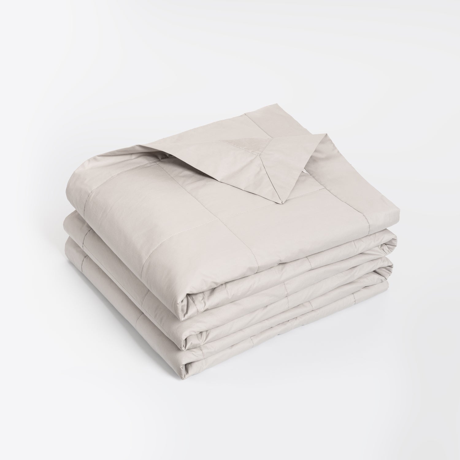 A neatly folded light beige comforter or duvet with matching pillowcases, stacked on a clean white background.