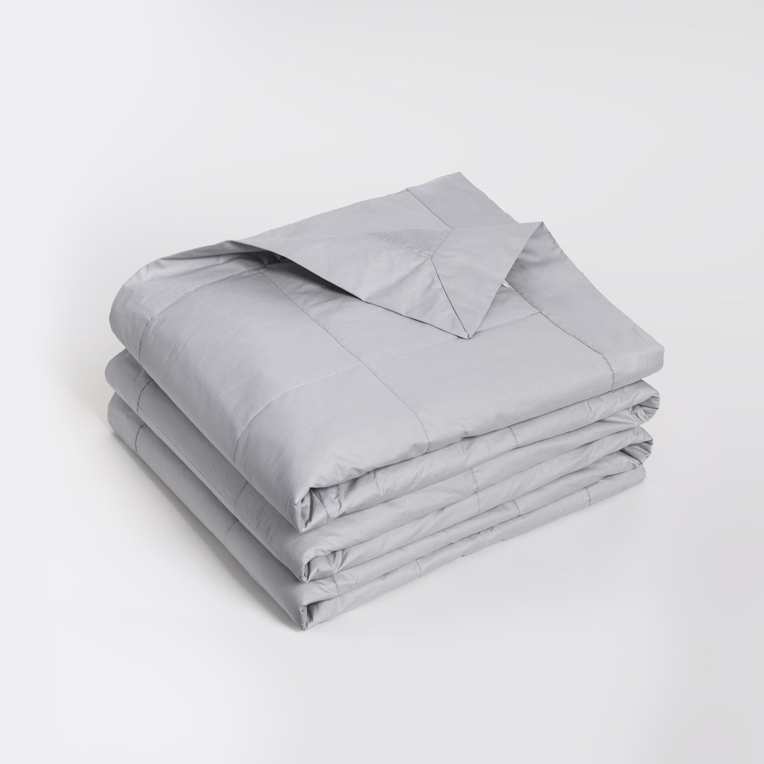 A folded light gray quilted comforter or duvet with a matching pillowcase, neatly stacked on a clean white studio background.