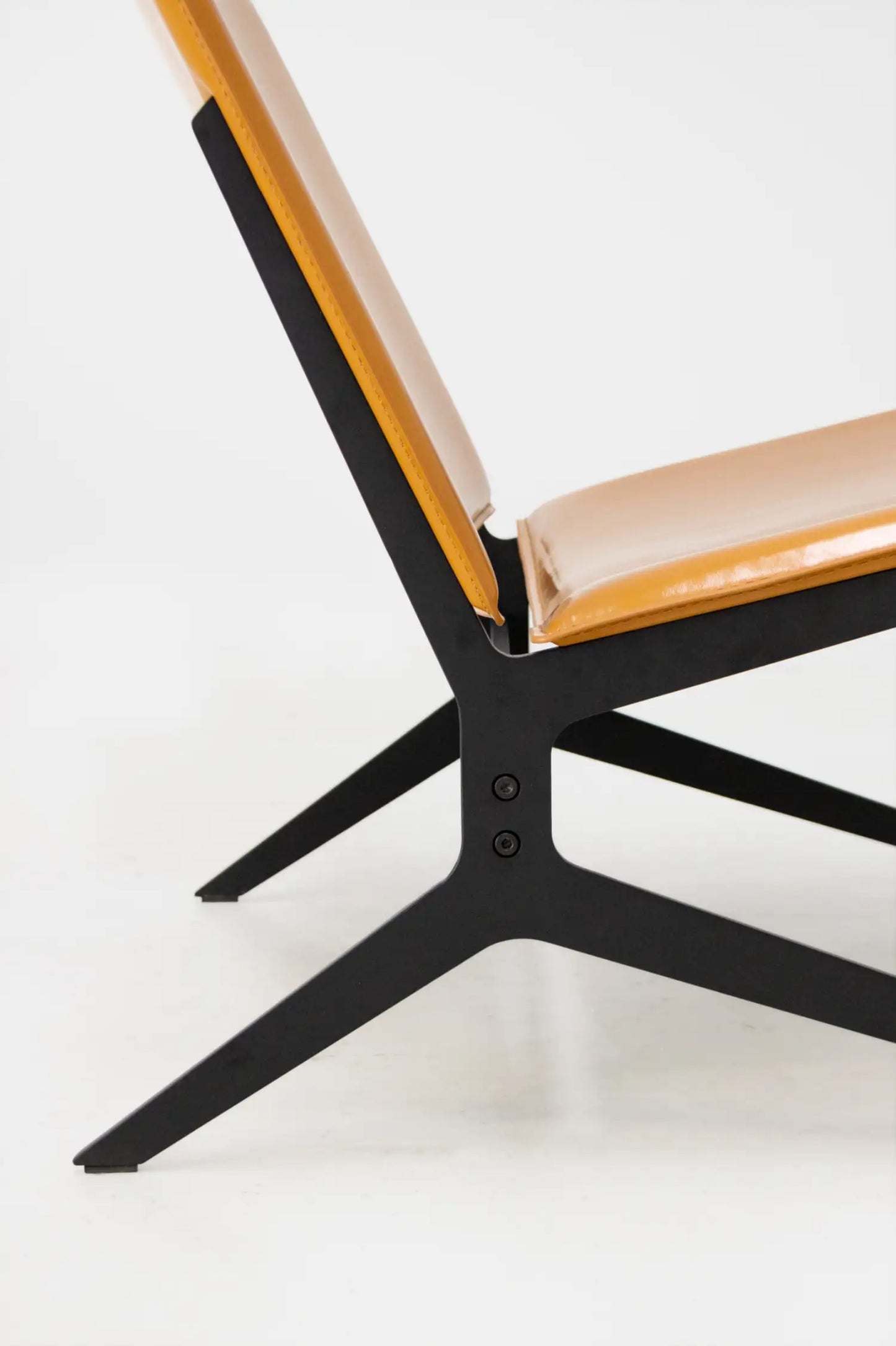 Close-up of a chair with black metal frame and beige cushion on a white background