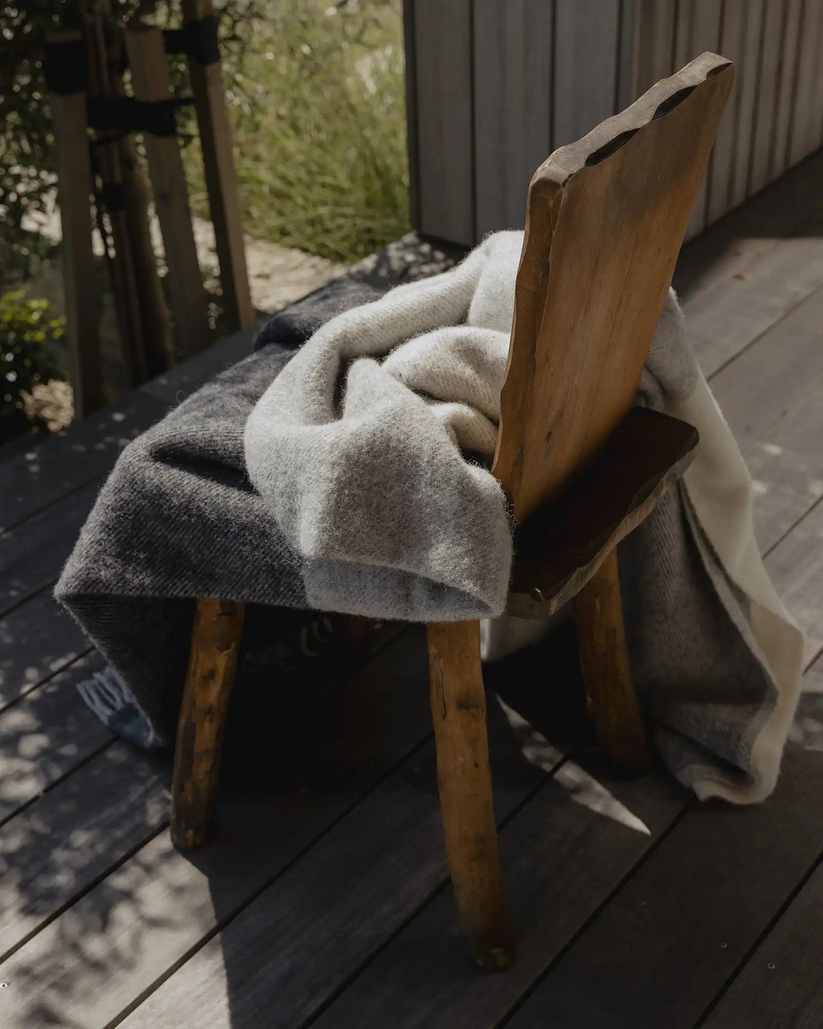 Wooden chair with a blanket draped over it on a wooden deck