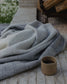 Gray blanket draped over a surface with a small brown container nearby.