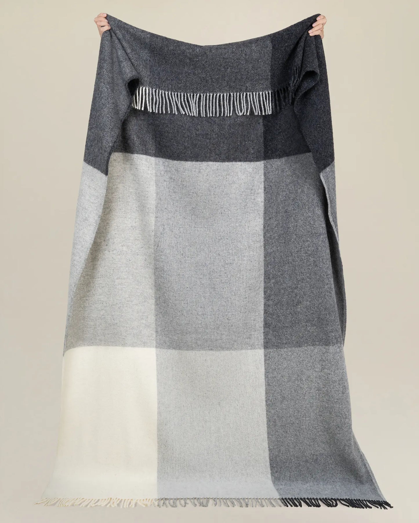 Gray and white checkered blanket draped over a person on a beige background