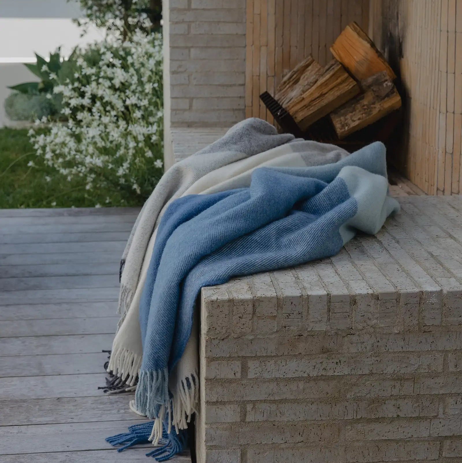 Blue and beige blanket draped over a stone ledge with a fireplace in the background.