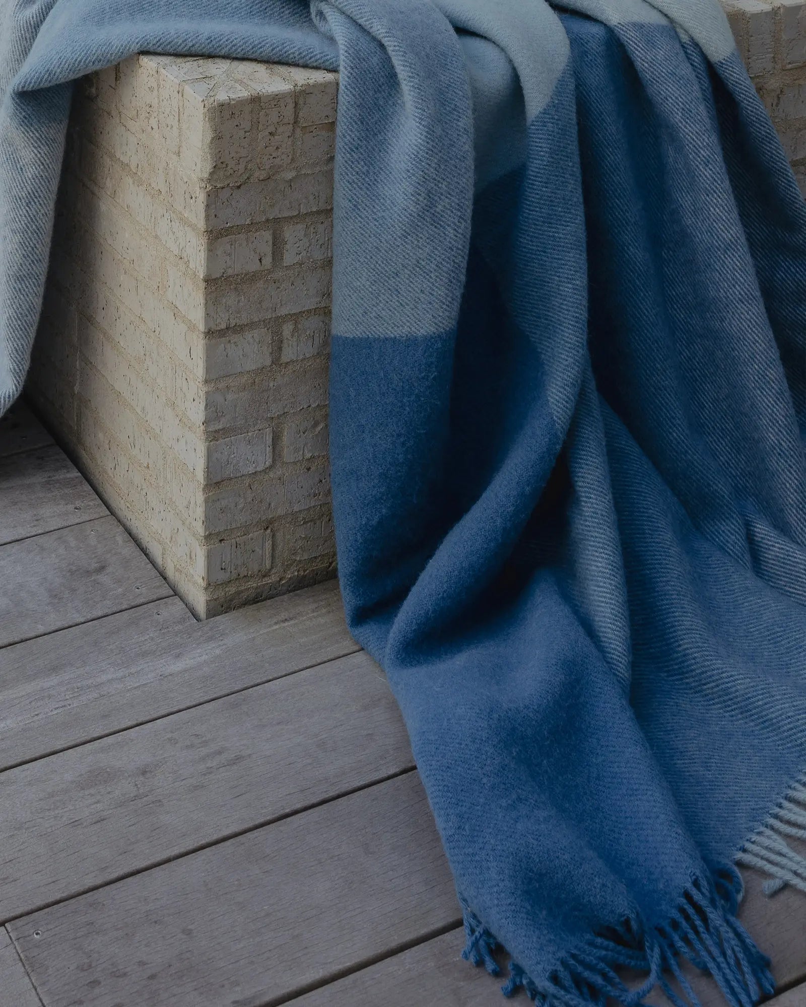 Blue blanket draped over a stone block on a wooden surface