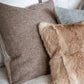 Decorative pillows on a bed with a textured headboard
