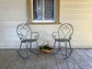 Two metal rocking chairs on a wooden deck with a window in the background.