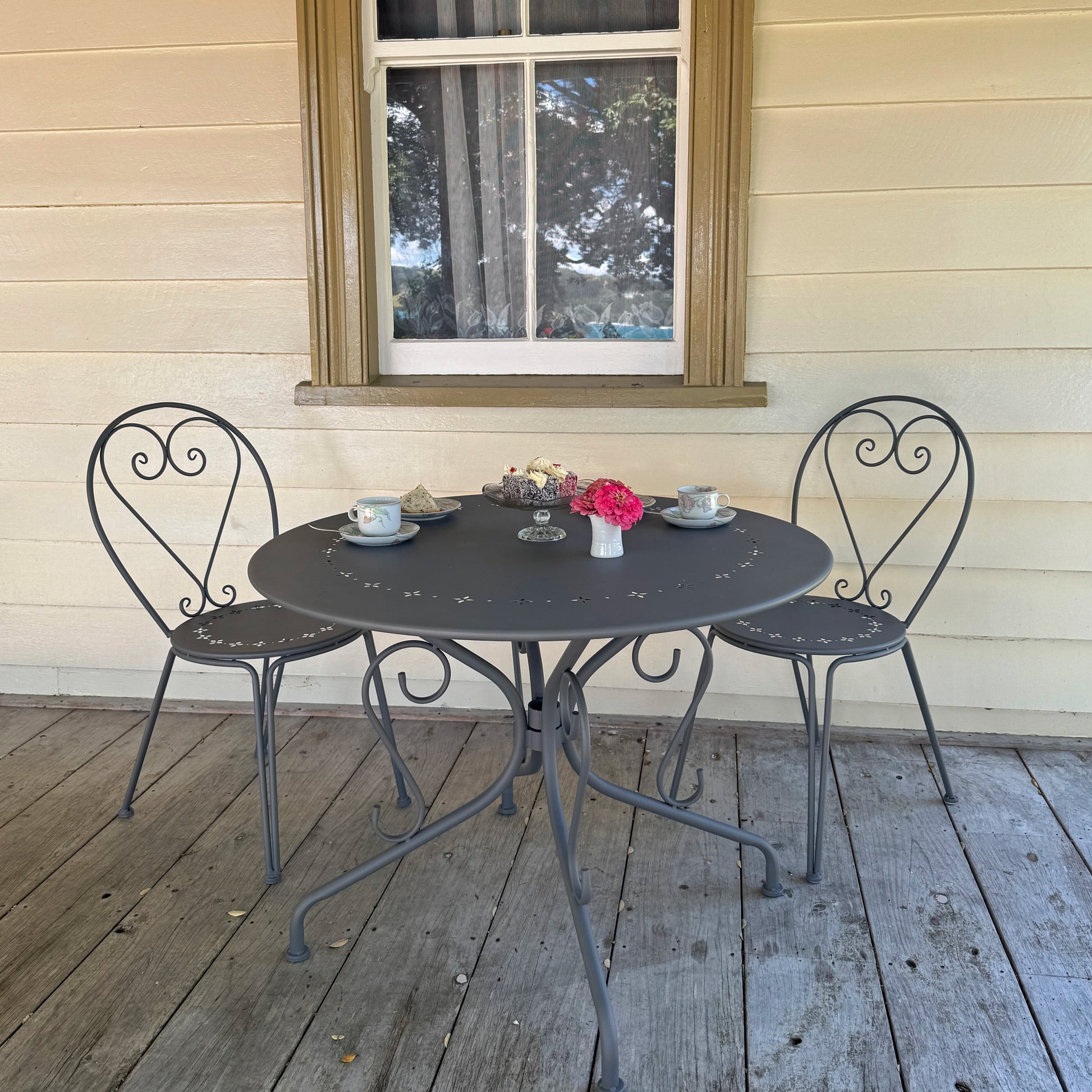 Outdoor patio set with a round table and four chairs on a wooden deck.