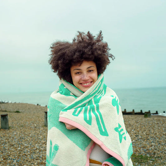 Person wrapped in a towelwith a beach and ocean in the background