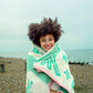 Person wrapped in a towelwith a beach and ocean in the background