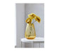 Yellow vase with flowers on a white table against a light gray wall