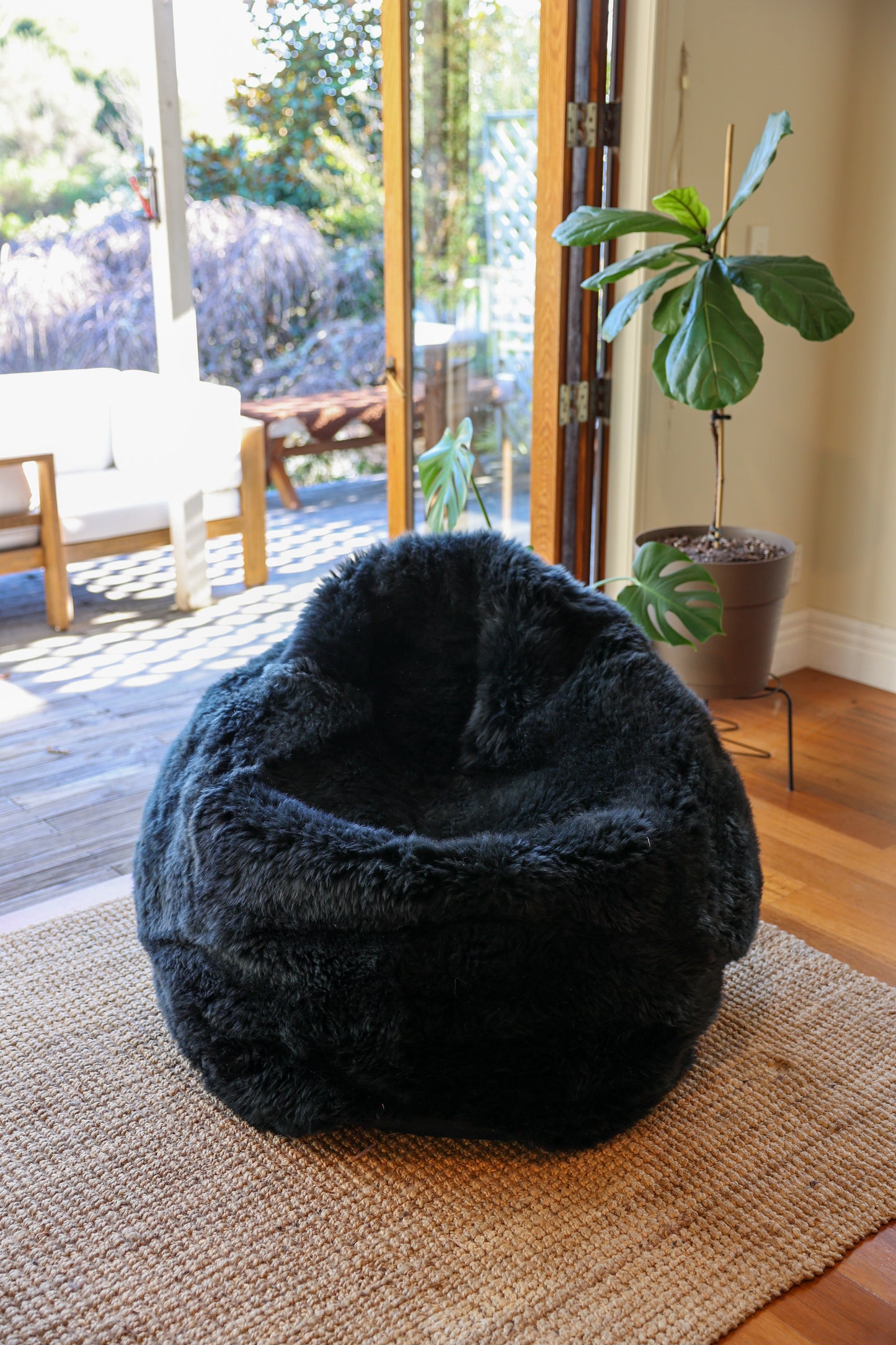 Black  bean bag chair on a textured rug with a plant and patio in the background