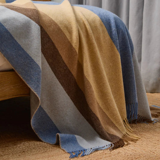 Colorful striped blanket draped over a wooden chair with a neutral background