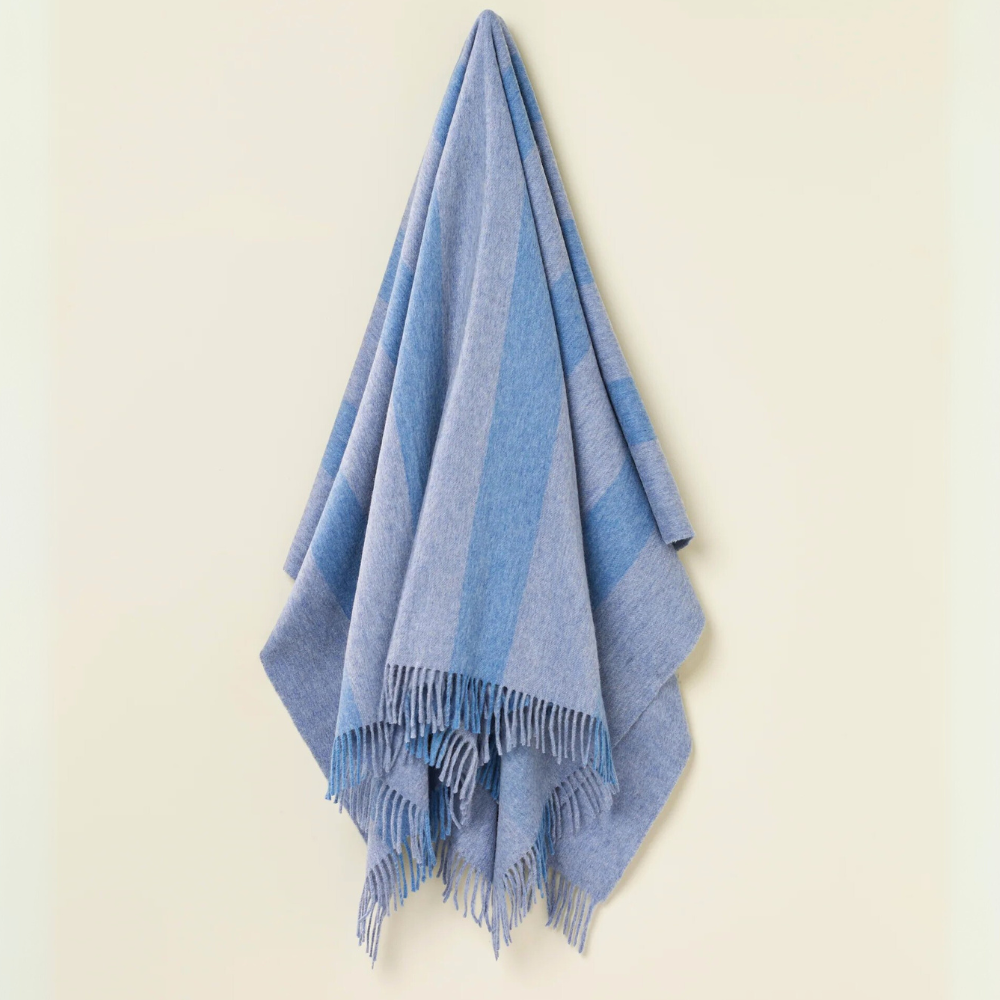 Blue striped merino throw blanket with fringe on a beige background