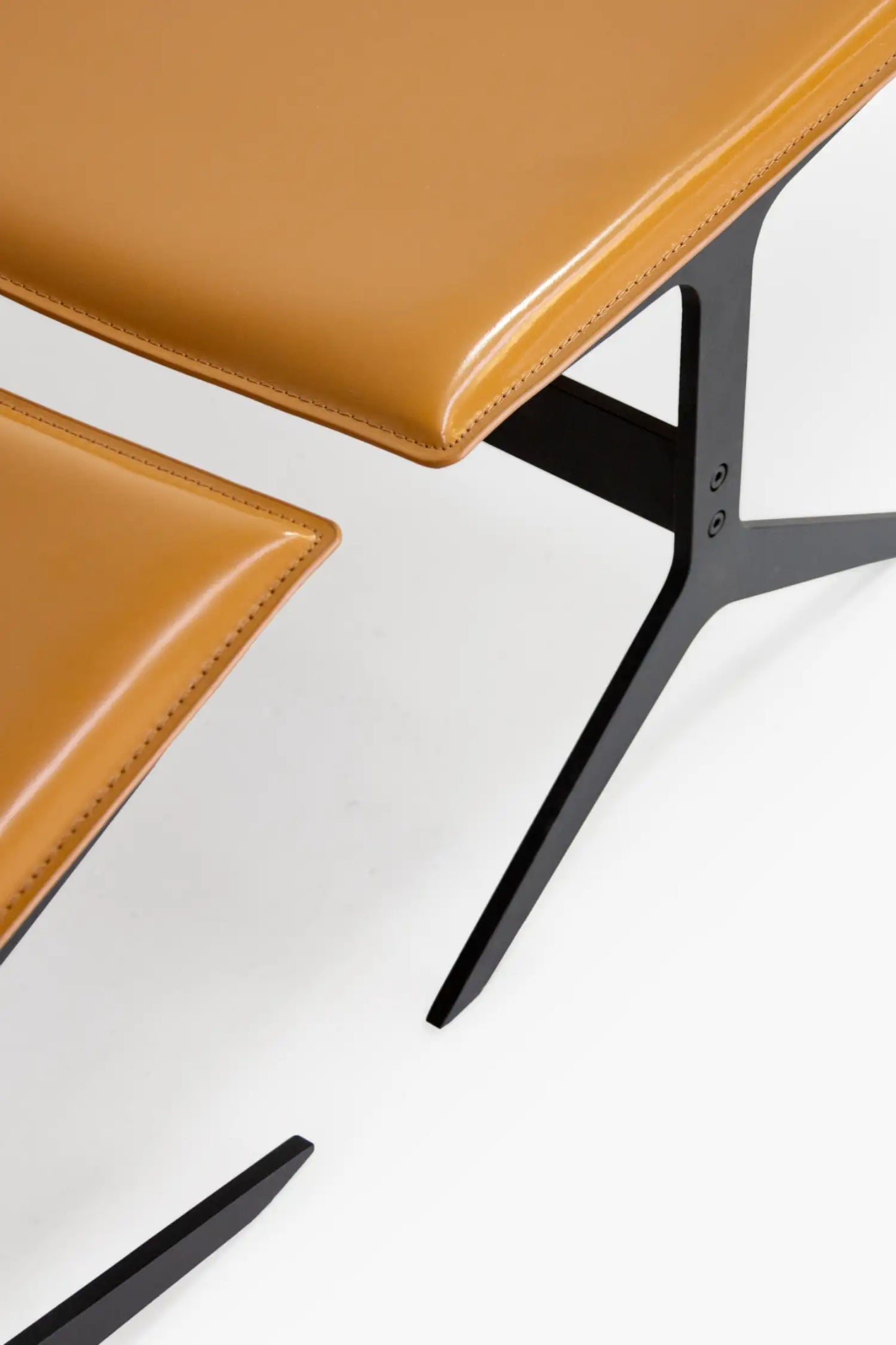 Two brown leather chairs with black metal legs on a white background