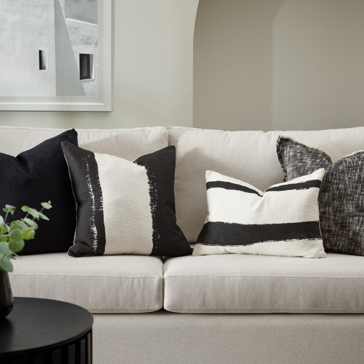 White sofa with black and white patterned cushions in a living room setting.